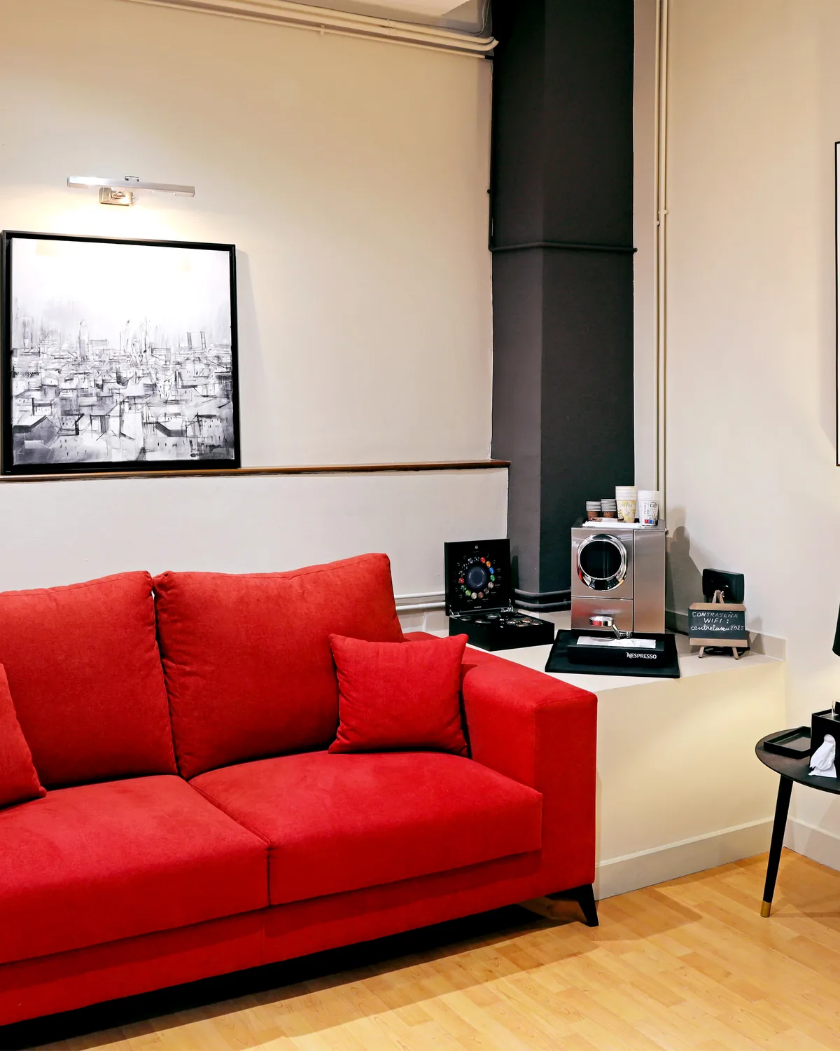 Renovated waiting area with a red sofa and artwork at Centre Revisions La Seu
